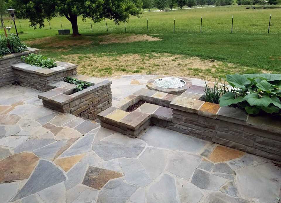 Brick and stone hardscaping with built-in walls, gardens, steps, and firepit built by stone patio contractor American Masonry Arts