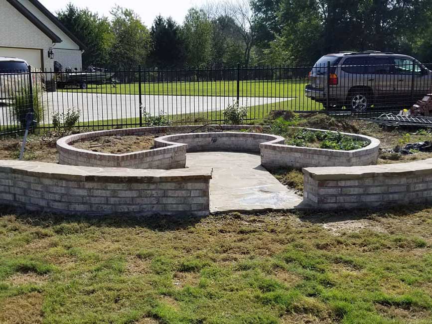 Brick and stone hardscaping with built-in walls, gardens, and walkway built by stone patio contractor American Masonry Arts